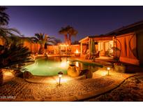 Serene backyard pool area with lush tropical landscaping and a cozy fire pit under the covered patio at 11182 S Hopi Dr, Goodyear, AZ 85338