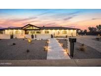 Inviting front exterior featuring a well-lit, stone pathway leading to a modern home with manicured landscaping at 12201 N 65Th St, Scottsdale, AZ 85254