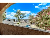 Balcony view featuring a colorful tree and a parking area under a sunny, partly cloudy sky at 12221 W Bell Rd # 249, Surprise, AZ 85378