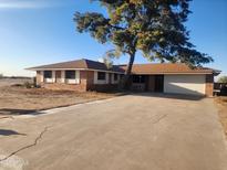 Charming brick home features a large tree in the front yard and a long driveway at 25050 W Boonne Dr, Casa Grande, AZ 85193