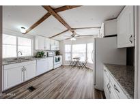 Bright kitchen features white cabinetry, granite countertops, wood-look flooring, and a cozy breakfast nook at 652 S Ellsworth Rd # 92, Mesa, AZ 85208