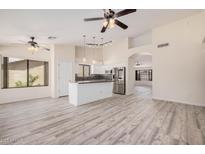 Bright living room open to the kitchen features modern floors, neutral paint, and lots of natural light at 11318 S Hopi Dr, Goodyear, AZ 85338