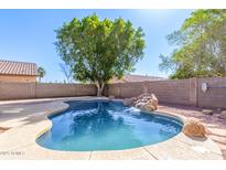 Backyard pool with rock waterfall feature surrounded by mature trees under a clear blue sky at 11359 E Elena Ave, Mesa, AZ 85208