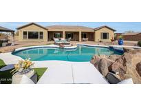 Inviting backyard pool area features lounge seating, rock accents, and a covered patio for relaxing and entertaining at 14507 W Christy Dr, Surprise, AZ 85379