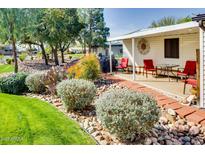 Charming home exterior with landscaped yard, red brick path, and covered patio area with seating at 17200 W Bell Rd # 2221, Surprise, AZ 85374