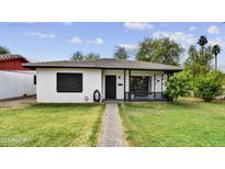 Charming single story home features a well-manicured lawn and a brick walkway, complemented by lush trees at 2045 W Orange Dr, Phoenix, AZ 85015