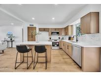 Spacious kitchen with stainless steel appliances, wood cabinets, tile backsplash and a center island with breakfast bar seating at 3037 E Pueblo Ave, Mesa, AZ 85204