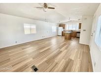 Bright living room open to kitchen featuring wood-look flooring, ceiling fan, and large windows at 318 S Crismon Rd # 83, Mesa, AZ 85208