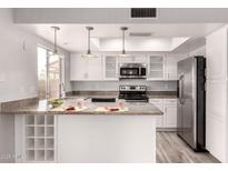 Well-lit kitchen featuring white cabinetry, stainless steel appliances, granite countertops, and a functional layout at 4701 E Walatowa St, Phoenix, AZ 85044