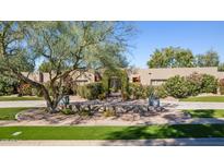 Charming home featuring mature landscaping, green lawn and an inviting entrance with a lovely shade tree at 7720 E Vaquero Dr, Scottsdale, AZ 85258