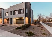 Modern townhome featuring a two-car garage, xeriscaped yard and a neutral colored exterior at 1936 W Kinfield Trl, Phoenix, AZ 85085
