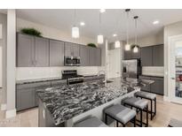 This kitchen features a large granite island, gray cabinets, stainless steel appliances, and wood flooring at 1936 W Kinfield Trl, Phoenix, AZ 85085
