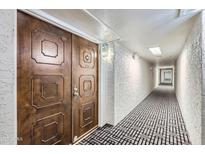 Long hallway featuring textured walls and geometric carpeting leading to the unit entrance at 7950 E Camelback Rd # 211, Scottsdale, AZ 85251