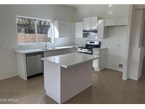 Bright kitchen with white cabinetry, stainless steel appliances and a center island, perfect for Gathering meals and entertaining at 21443 N 29Th Dr, Phoenix, AZ 85027