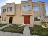 Two-story home featuring a stucco facade, red double-door entry, and well-maintained front lawn at 4258 N 68Th Ln, Phoenix, AZ 85033