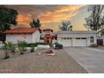 Stunning home with a three-car garage, desert landscaping, and a red-tile roof at sunset at 8717 E Spanish Barb Trl, Scottsdale, AZ 85258