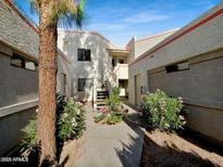 Condo exterior with mature landscaping, neutral paint scheme, and visible stairs to upper units at 985 N Granite Reef Rd # 134, Scottsdale, AZ 85257
