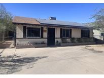 Charming single-story home featuring solar panels, a tidy front yard, and security bars on the windows at 1232 S 10Th Ave, Phoenix, AZ 85007