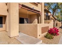 Tan apartment building exterior with a private balcony surrounded by decorative concrete wall and bushes at 1351 N Pleasant Dr # 1045, Chandler, AZ 85225