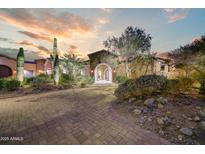 Desert home exterior with landscaped front yard, stone facade, and a paver driveway at sunset at 14371 E Kalil Dr, Scottsdale, AZ 85259