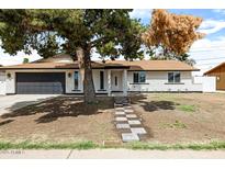 Charming single-story home featuring a brick exterior, a dark gray garage door, and a landscaped front yard at 2032 W Eugie Ave, Phoenix, AZ 85029