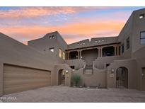 Elegant multi-story home with arched gated entry and covered balcony, set against a vibrant sunset sky at 36601 N Mule Train Rd # C38, Carefree, AZ 85377