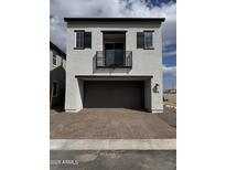 Modern two-story home featuring a balcony and a two-car garage with a brick paver driveway at 2443 W Rowel Rd, Phoenix, AZ 85085