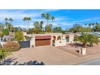 Charming exterior featuring a terra cotta roof, a large driveway, and a backdrop of mature palm trees at 4114 E Desert Cove Ave, Phoenix, AZ 85028