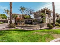 Community sign for The Carlyle Condominiums with lush landscaping and well-maintained grounds under a clear blue sky at 5303 N 7Th St # 242, Phoenix, AZ 85014