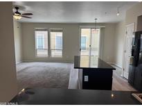 Bright open-concept living room featuring a ceiling fan, large windows, and sliding glass door at 18250 N Cave Creek Rd # 105, Phoenix, AZ 85032