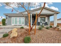 Charming single-story home with a covered porch and landscaped front yard featuring decorative rock and young trees at 22808 E Roundup Way, Queen Creek, AZ 85142