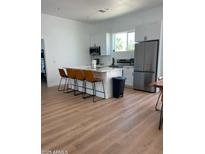 Bright open kitchen with stainless steel appliances, island, and sleek white cabinets at 2440 W Morten Ave, Phoenix, AZ 85021