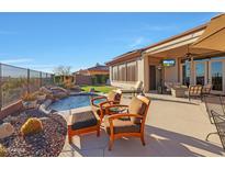 Inviting backyard featuring a pool with a waterfall, comfortable seating, and a covered patio with TV at 3109 W Summit Walk Ct, Anthem, AZ 85086