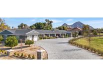 Charming single-story home with stone accents, lush landscaping, and a circular driveway with mountain views at 3702 E Camelback Rd, Phoenix, AZ 85018