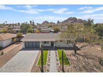 Charming home with desert landscaping, brick driveway, modern garage door, and mountain views at 5927 E Edgemont Ave, Scottsdale, AZ 85257