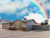 Charming single-story brick home with a gravel yard and a vibrant rainbow in the clear blue sky above at 76 N 133Rd St, Chandler, AZ 85225