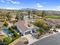 Stunning aerial view of home with pool, lush landscaping, and lake views at 15563 W Roanoke Ave, Goodyear, AZ 85395