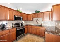 Well-lit kitchen featuring warm wood cabinetry, stainless steel appliances, and granite countertops at 9455 E Raintree Dr # 2032, Scottsdale, AZ 85260