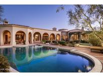 Beautiful swimming pool at dusk, surrounded by the well-lit home exterior and decorative landscaping at 9820 E Thompson Peak Pkwy # 841, Scottsdale, AZ 85255