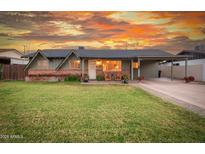 Charming single-story home featuring a lush green lawn, brick accents, and a covered porch with inviting rocking chairs at 1109 E 8Th St, Mesa, AZ 85203