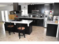 Modern kitchen with stainless steel appliances, mosaic backsplash, and a large center island at 13219 W Aleppo Dr, Sun City West, AZ 85375