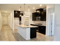 Open-concept kitchen boasts dark cabinetry, stainless steel appliances, and a granite island with pendant lighting at 14132 W Valentine St, Surprise, AZ 85379