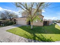 Two-story home boasts a neutral exterior, tidy lawn, and charming landscaping with a mature shade tree at 15646 N 20Th Ave, Phoenix, AZ 85023