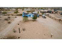 Aerial view of a blue single story house with a white door and a desert landscape with solar panels on the roof at 30446 W Portland St, Buckeye, AZ 85396