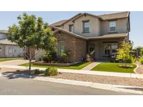 Charming two-story home with a stone facade, manicured lawn, and lovely landscaping at 10713 E Tesla Ave, Mesa, AZ 85212