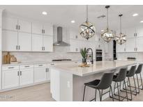 Bright kitchen featuring white cabinets, stainless steel appliances, and a large quartz countertop island with pendant lighting at 10713 E Tesla Ave, Mesa, AZ 85212