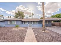 Charming single-story home with blue painted brick and a well-manicured, desert landscaped front yard at 10844 N 37Th St, Phoenix, AZ 85028