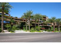Beautiful multi-story condominium building with lush greenery and palm trees against a clear blue sky at 7121 E Rancho Vista Dr # 1008, Scottsdale, AZ 85251