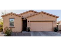 Charming single-story home with a tan exterior, a two-car garage, and simple desert landscaping at 18842 N Lariat Rd, Maricopa, AZ 85138