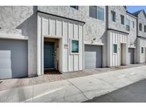 View of the home's stucco exterior, light-gray garage door, and the quaint blue door and decorative brick pathway at 2228 W Harmont Dr, Phoenix, AZ 85021